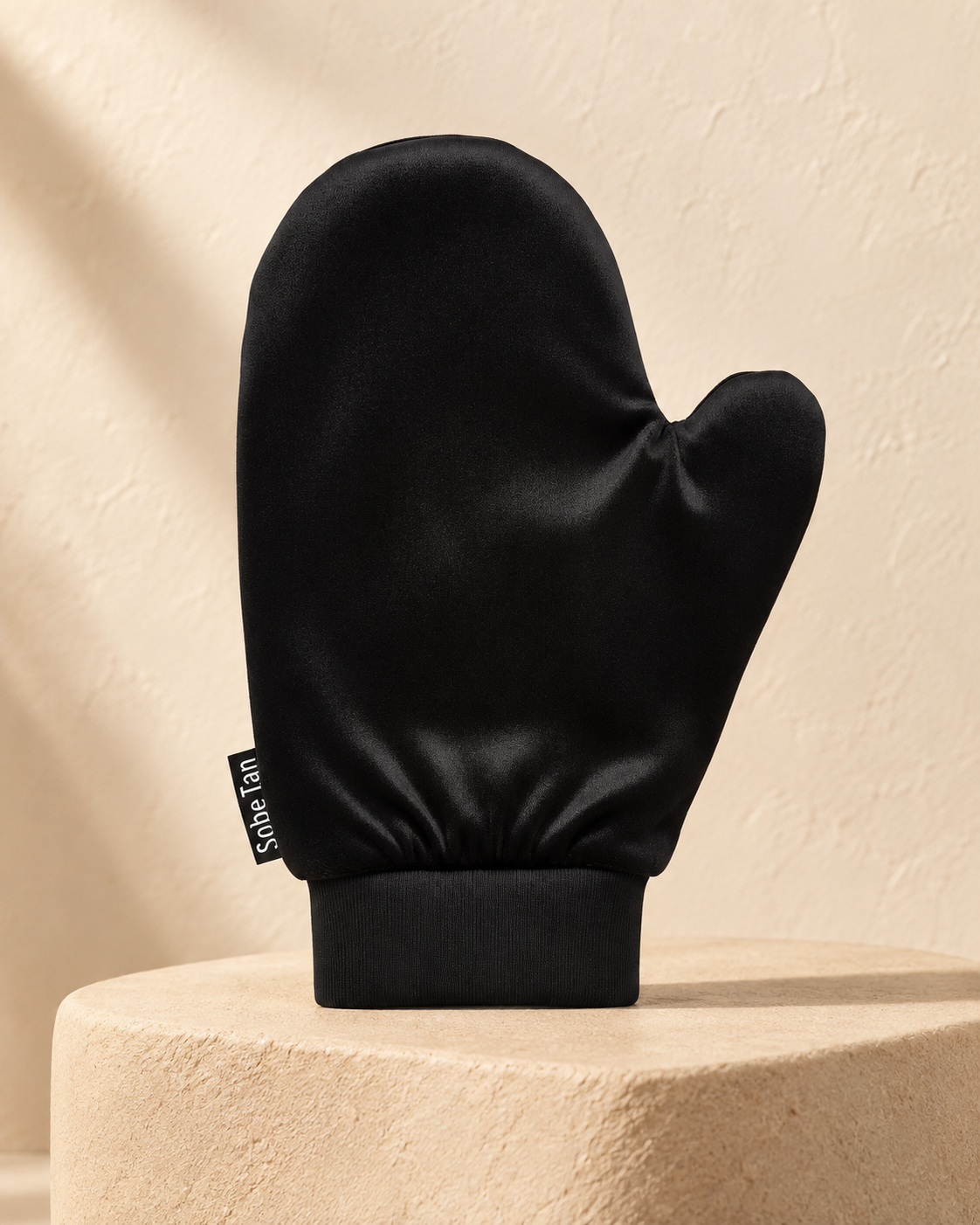 SoBe Tan self-tanning mitt standing on warm stone